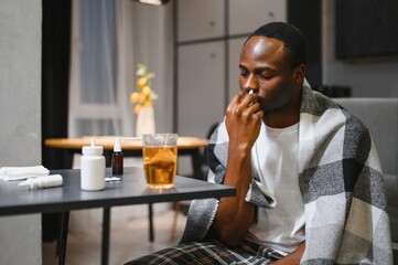 Man using nasal spray for relief from allergies or cold, sitting in a cozy home setting