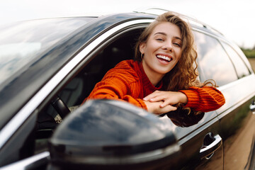 Happy woman resting and enjoying travel out of the car window. Car Adventure. Travel, tourism,...
