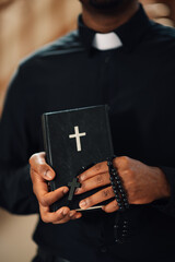 Priest holding holy bible and rosary beads