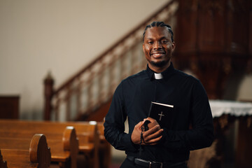 Young priest smiling holding bible in church