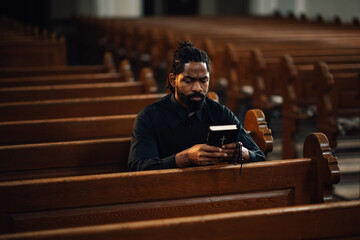 Priest reading holy book sitting on bench in church
