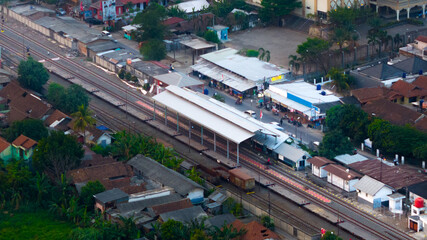 Fototapeta premium Aerial view of a bustling train station amidst urban settlement at twilight
