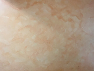 A tan wall with a pattern on it. The pattern is made up of small squares. The wall is smooth and has a slightly rough texture