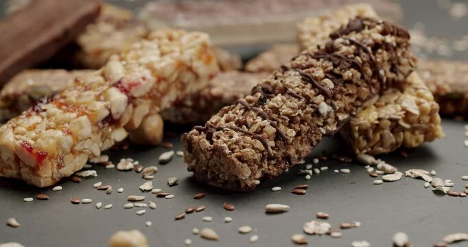 Close-up image of various nut and cereal energy bars arranged on a dark surface. Includes chocolate, seeds, and grains. Ideal for healthy snack, nutrition, and fitness concept. Cereal Energy Bar