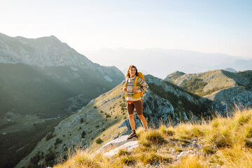 Woman tourist standing at mountains with backpack admiring landscape. Nature, active life, travel.