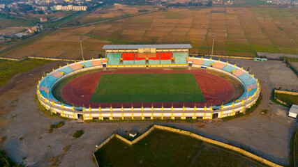 Aerial view of a vibrant sports stadium basking in the warm glow of sunrise, ready for action-packed events