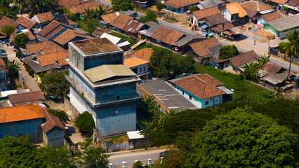 An aerial view of a cozy, tropical village with rustic buildings nestled amidst lush greenery, capturing the essence of rural life and community