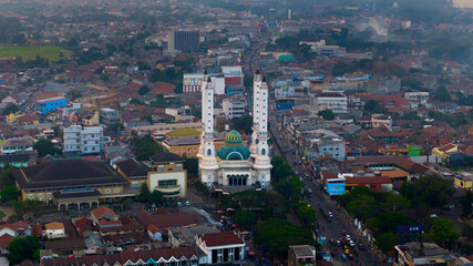 Aerial view of a bustling city street leading towards an iconic mosque with tower amid a sprawling urban landscape at dusk