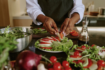 Medium close up of unrecognizable female hands decorating dish with tomatoes and mozzarella