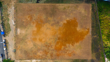 Aerial view of a parched playing field with contrasting textures, illustrating themes of drought and the impact of climate change on local environments