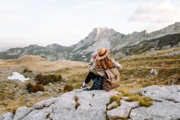 A woman stands on rocky terrain, gazing out at the breathtaking landscape before her. Autumn. Active lifestyle.