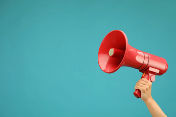 Woman holding megaphone speaker on blue background, closeup. Space for text