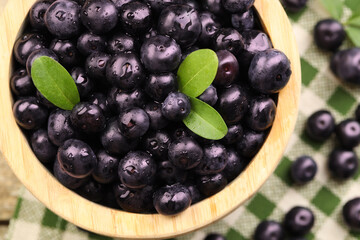 Ripe acai berries and leaves in bowl on table, top view