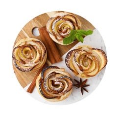 Freshly baked apple roses, cinnamon sticks, anise star and mint isolated on white, top view. Puff pastry
