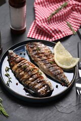 Plate with delicious grilled mackerel, rosemary and lemon served on dark textured table