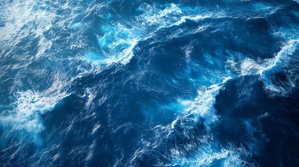 Fototapeta premium Aerial view of deep blue ocean waves crashing with foam, showcasing the power and beauty of nature.