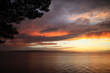 Picturesque sky with clouds at sunset on the Croatian coast. Clouds and sea in the rays of the setting sun on an autumn evening