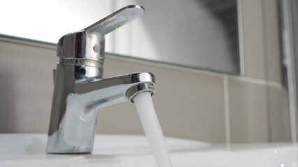 Hand close up water from faucet in sink, faucet, woman stop wasting water, flood, running water for washing in bathroom
