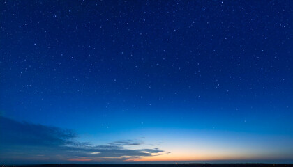 Beautiful background of a starry sky in vibrant tones, transitioning from a soft orange glow on the horizon to the deep indigo of night, capturing the blue hour of twilight