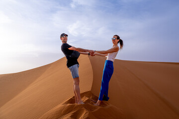 Couple holding hands on top of dune in Merzouga