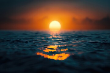 Obraz premium Out of focus sun setting over the ocean glowing orange with dark blue background