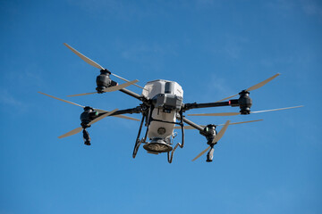 Large agricultural drone in flight, fertilizing a sown field.