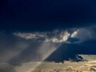 Sonnenstrahlen durchdringen dunklen Wolkenhimmel