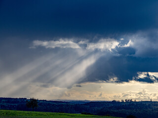 Sonnenstrahlen durchdringen dunklen Wolkenhimmel