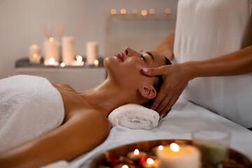 Cosmetologist masseur making relaxing head massage for young lady at modern luxury spa in romantic...