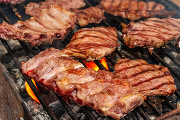 Close-up of juicy pork meat steaks, ribs and tenderloin grilling on the barbecue.