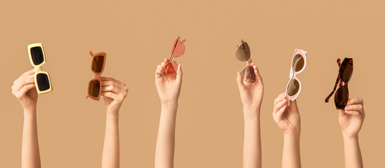 Female hands with different sunglasses on beige background