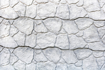 Close-up texture of a rugged stone wall. A detailed close-up of a rugged stone wall, displaying its textured surface and irregular stone patterns.