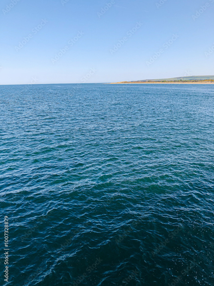 Wall mural seascape from kayak of clear blue ocean and island in distance and white fluffy clouds and blue sky