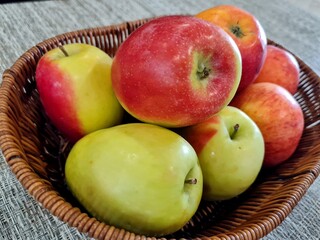 Green and red apples in a basket, close-up