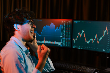 Successful business trader calling to broker, raising fist up with highest profit on global market online in real time at neon light modern office. Concept of stock exchange young businessman. Gusher.