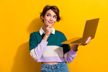 Portrait of pretty nice young girl hold laptop look empty space wear shirt isolated on yellow color...