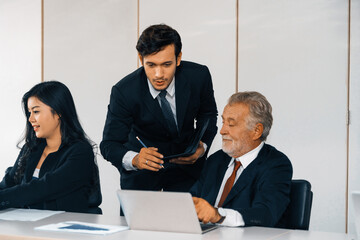 Senior caucasian manager working in office with assistance of young Asian business people and...