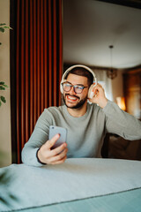 Young caucasian man listening to music or audio book at home