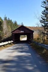 In the northeast, an old covered bridge over a river framed by fall foliage.