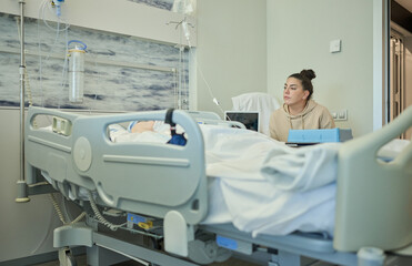 Young woman cares for and accompanies her elderly grandmother lying in bed in her hospital room...
