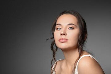 Beautiful young woman with natural makeup against grey background