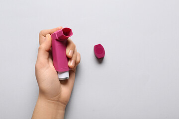 Child's hand with asthma inhaler on white background