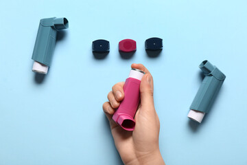 Child's hand with asthma inhalers on blue background