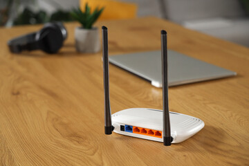 Modern wi-fi router on wooden table in room, back view
