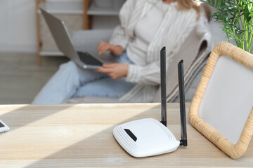 Modern wi-fi router with frame on shelf in room, closeup