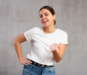Portrait of coquettish young woman standing in attractive position against light unicoloured...