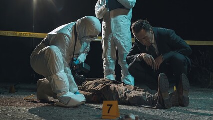 Detective and forensic scientists working hard at crime scene near headless body. Collection and...