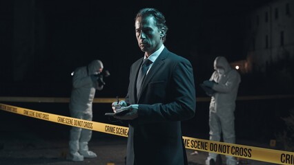 Detective inspecting area and taking notes in notebook at crime scene at night as forensic experts...