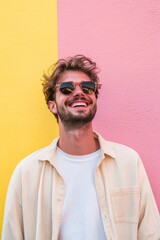Fototapeta premium Stylish young man in sunglasses smiling while standing against colorful wall