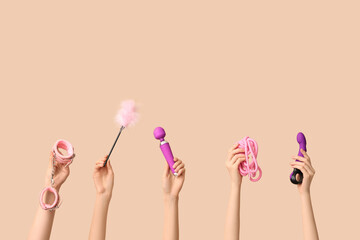 Female hands with different sex toys on brown background